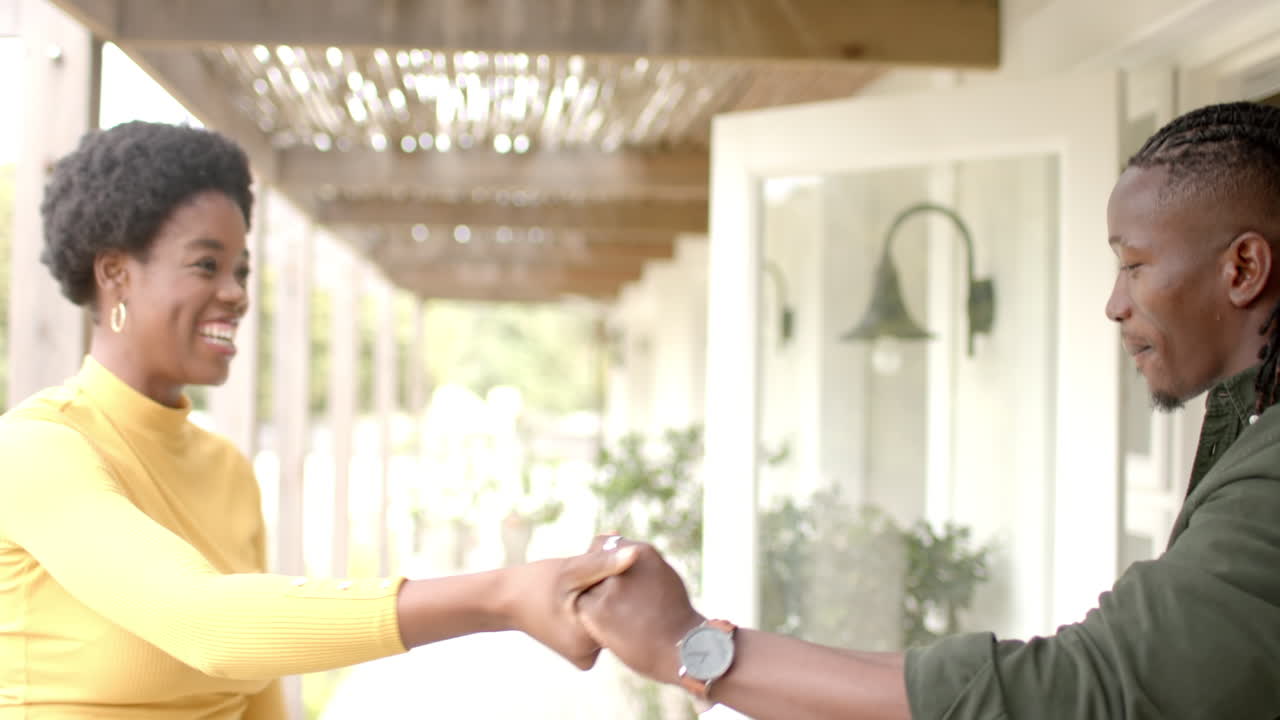 Smiling African american couple giving high five, enjoying time together at home