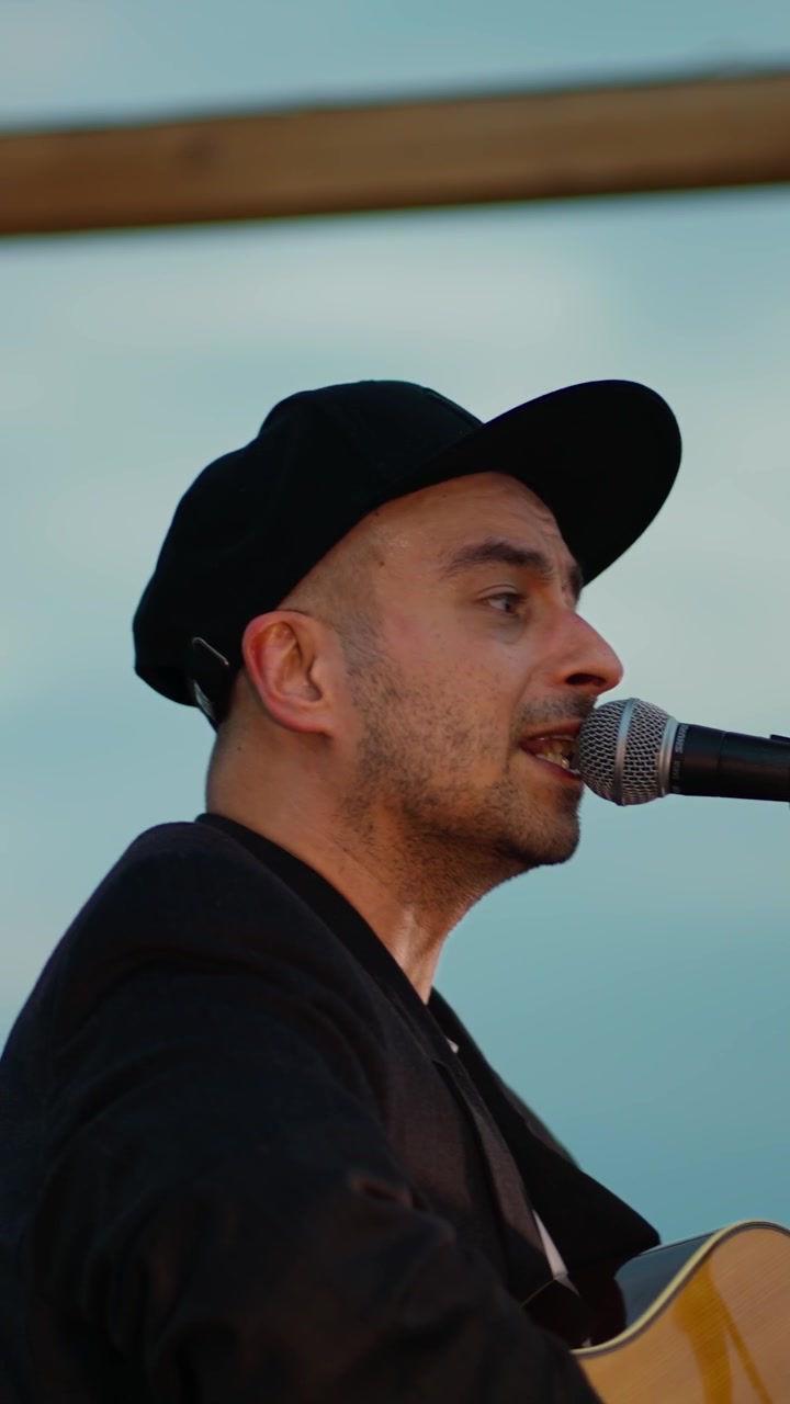Man in Cap Singing and Playing Acoustic Guitar Live Outdoors