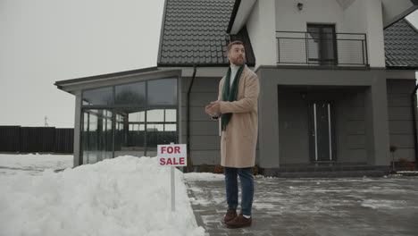 agente de bienes raíces poniendo un letrero en la nieve