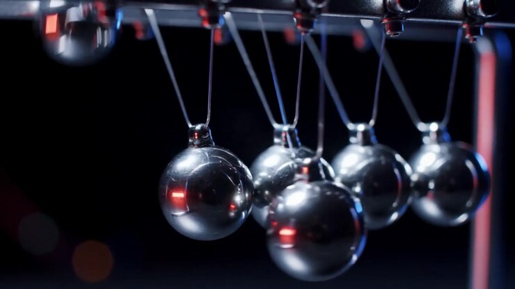 Newton's Cradle Swinging Metal Spheres in Dark Studio