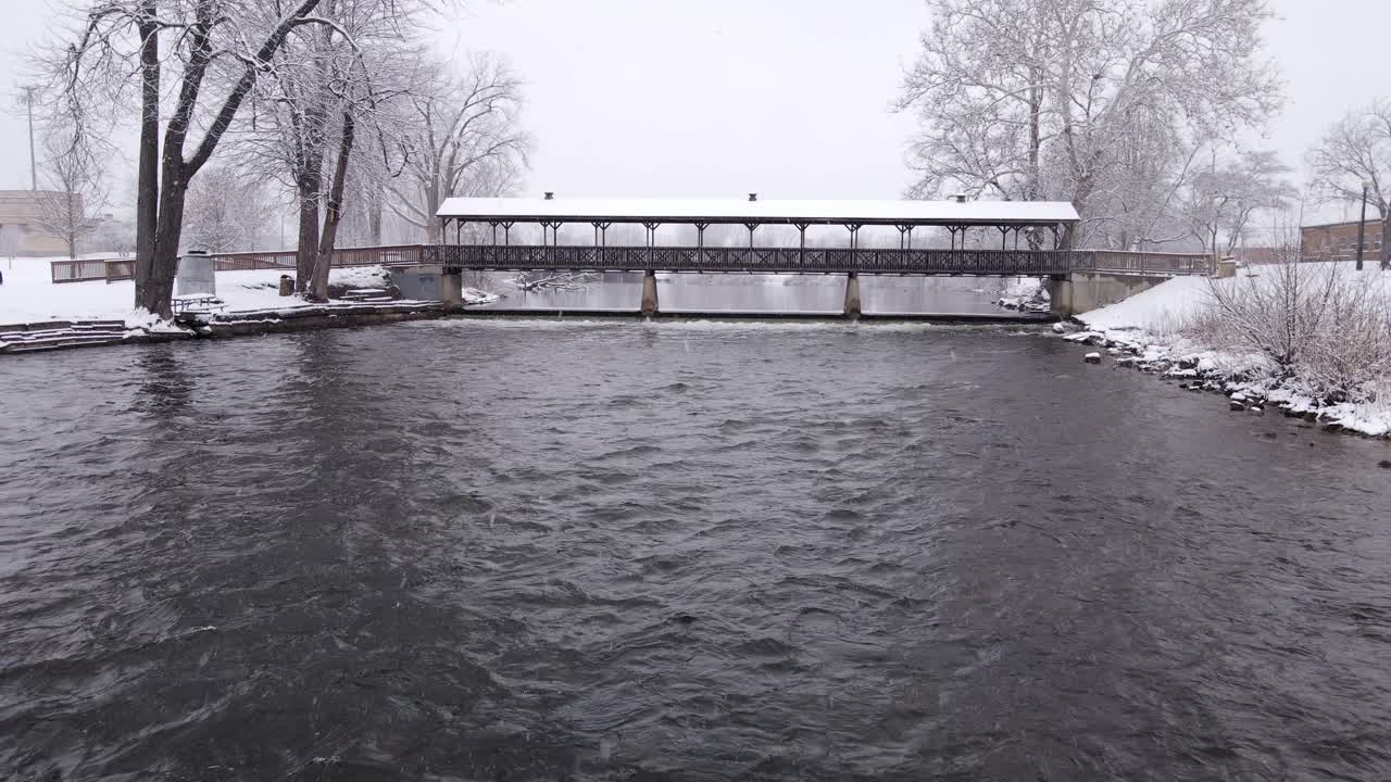 Iconic roofed bridge during heavy snowfall, aerial fly toward view