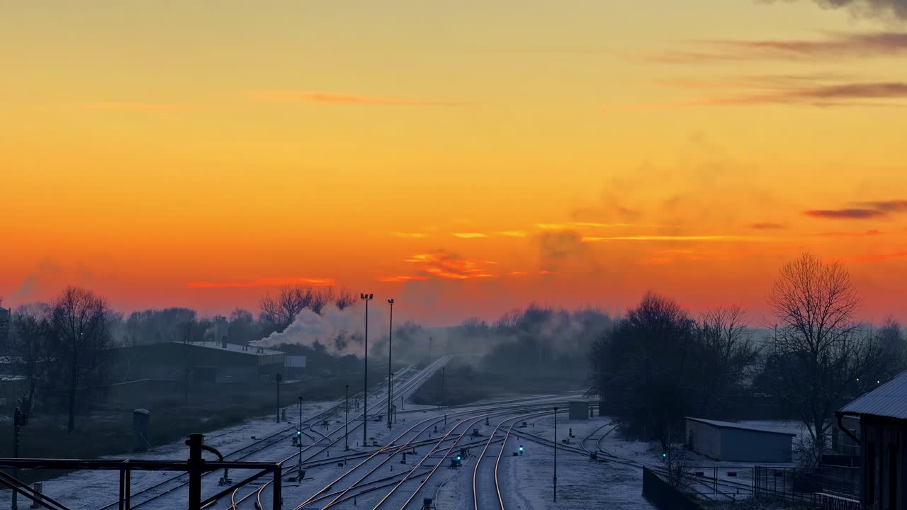 Kald morgensol over Jelgavas snødekte jernbanespor i Latvia, gyllen skyline