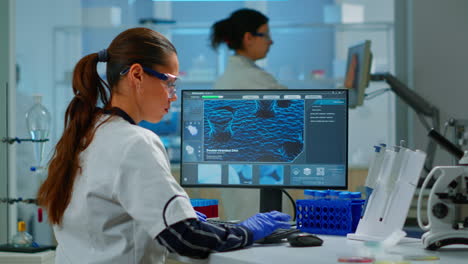 Laboratory doctor holding at blood sample and typing on computer