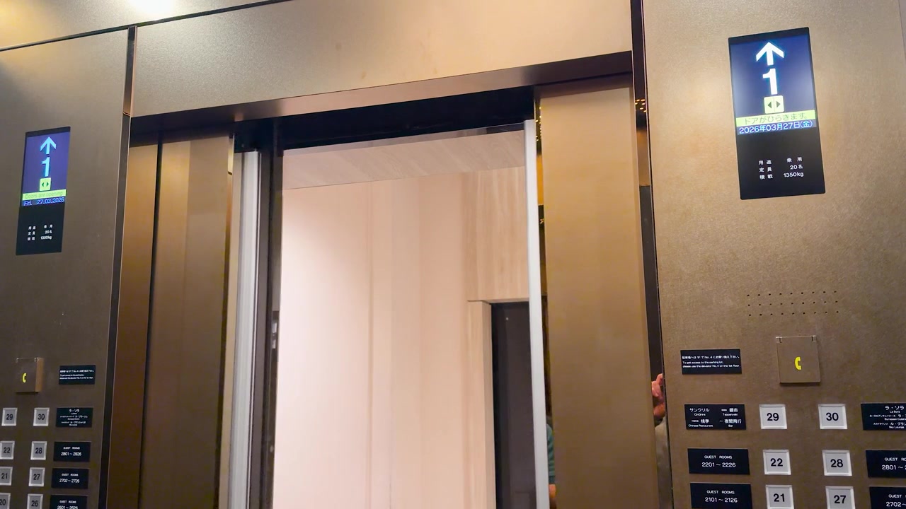Static shot of metallic elevator doors opening to reveal a bright modern hotel interior.