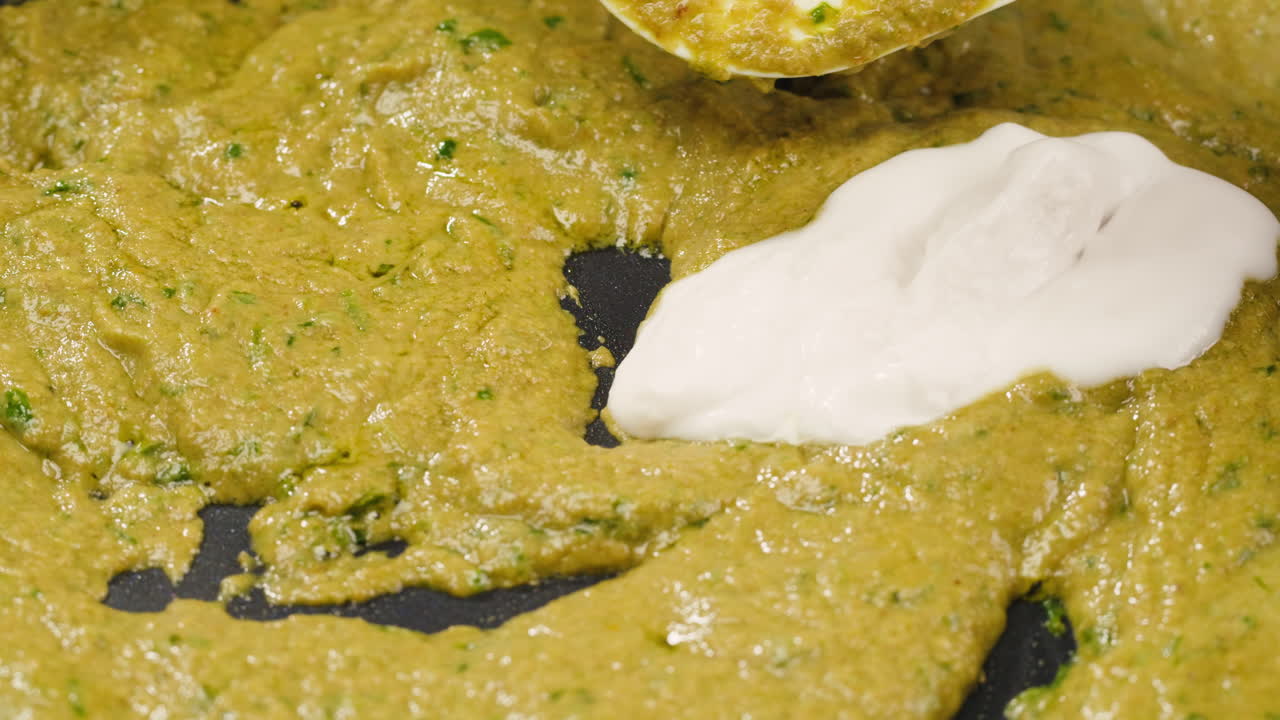 Food preparation with green sauce and white dairy product