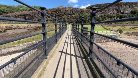Video-footage-walking-along-a-footpath-bridge-with-cast-wrought-iron-fencing-on-a-summer-day