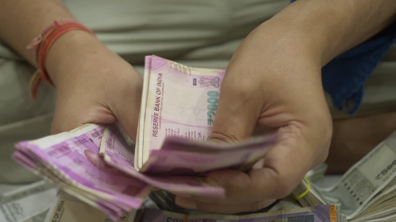 An Indian businessman counting 2000 Rupee banknotes, Cash in Hand Closeup, India, Selective focus