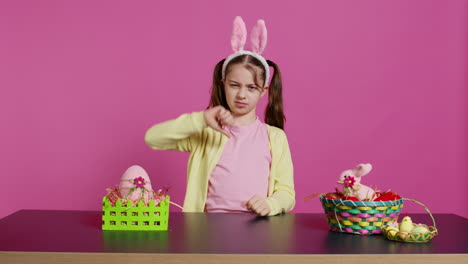 displeased unhappy child giving thumbs down in studio