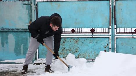 Man-Removing-Snow-With-A-Shovel-In-The-Yard---wide