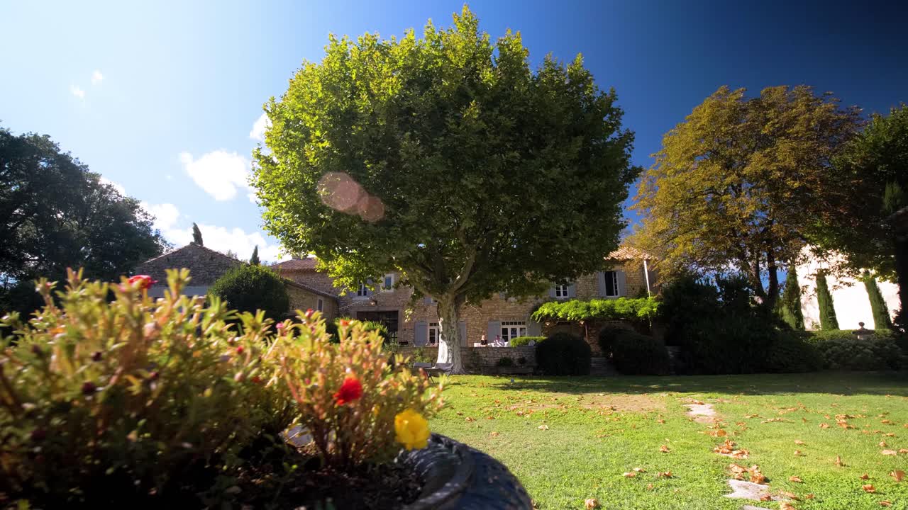 Ein wunderschön gepflegter Garten mit dem Haus im Hintergrund in Maison Goult, Frankreich. Die Szene zeigt eine perfekte Mischung aus natürlicher Schönheit und architektonischem Charme