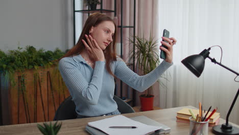 joven bloguera tomando retratos de selfie en su teléfono inteligente para los medios sociales vlog mientras trabaja en casa