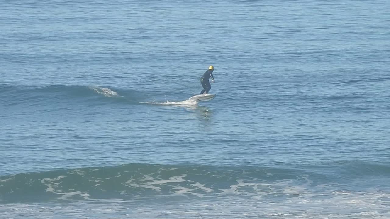 Foiler loses balance, breaking the pump rhythm as they fall off the hydrofoil, creating a splash.
