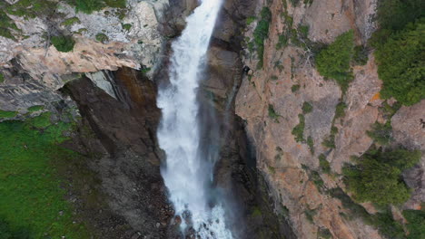 aerial shot barskoon waterfall in fairy tale canyon in kyrgyzstan, starting downward and then tilting to reveal falls, drone footage