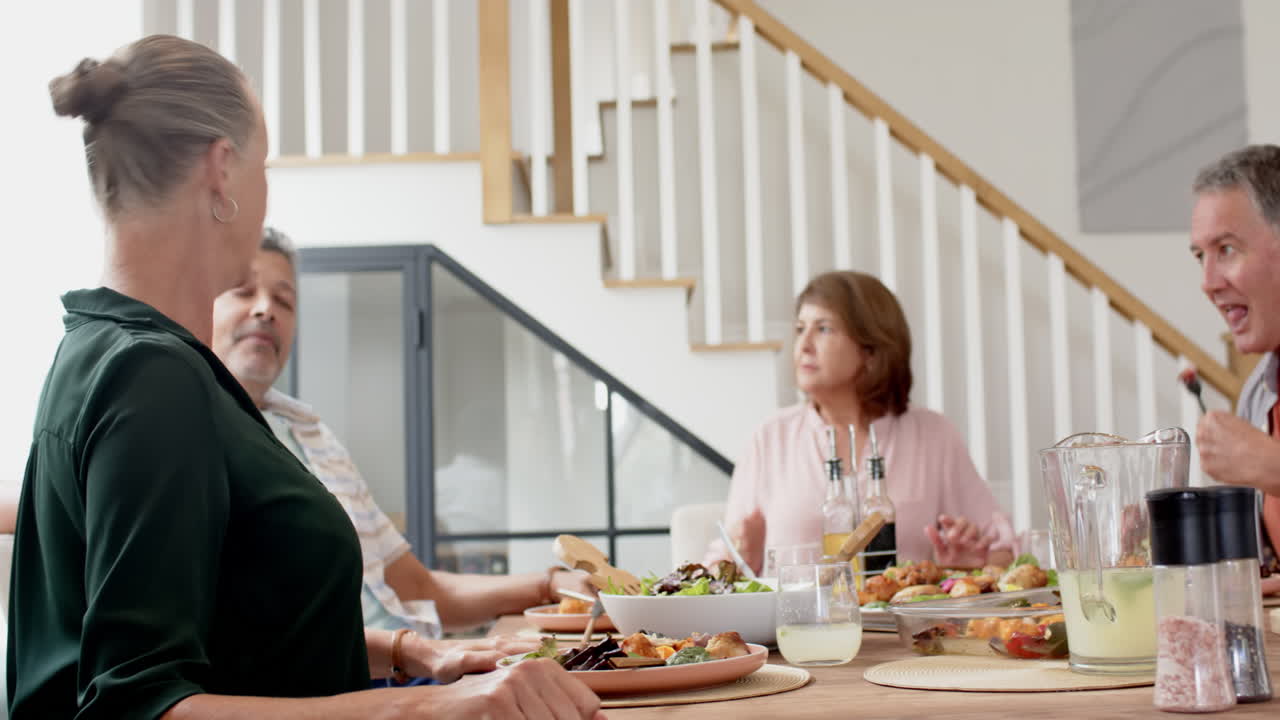 Senior friends enjoying meal together at dining table, sharing conversation
