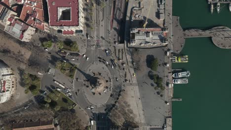 aerial: overhead shot of columbus monument roundabout in barcelona, spain with busy car traffic on sunny day [4k]