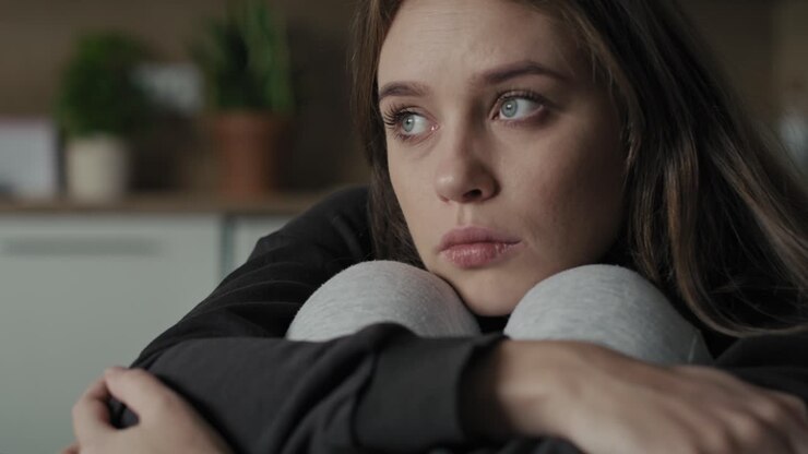 Sad young woman sitting at home and thinking.