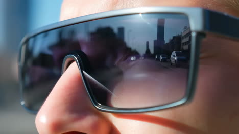 person wearing sunglasses with a reflection of an urban street