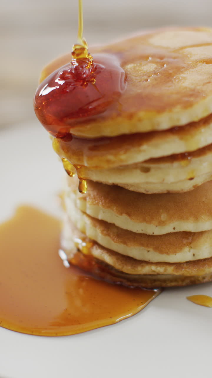 video vertical de jarabe de arce vertido en una pila de panqueques de estilo americano