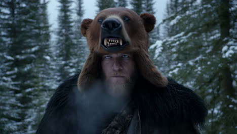man in bear head hat in snowy forest