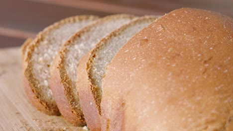 freshly baked homemade white bread with slices on wooden chopping board outside in natural morning sunlight with shallow dof. home baking footage with simple healthy ingedients 4k.