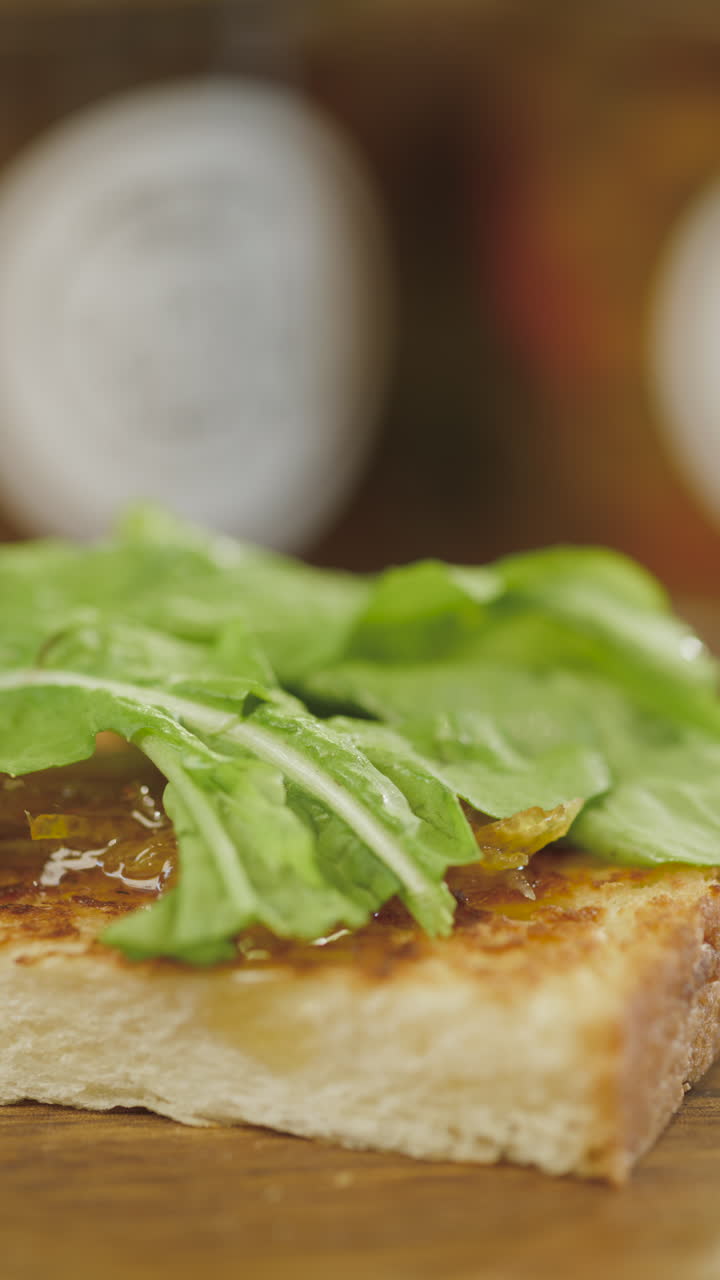 Primo piano di un panino artigianale con prosciutto stagionato, formaggio e rucola su pane croccante, in un contesto gastronomico sfocato