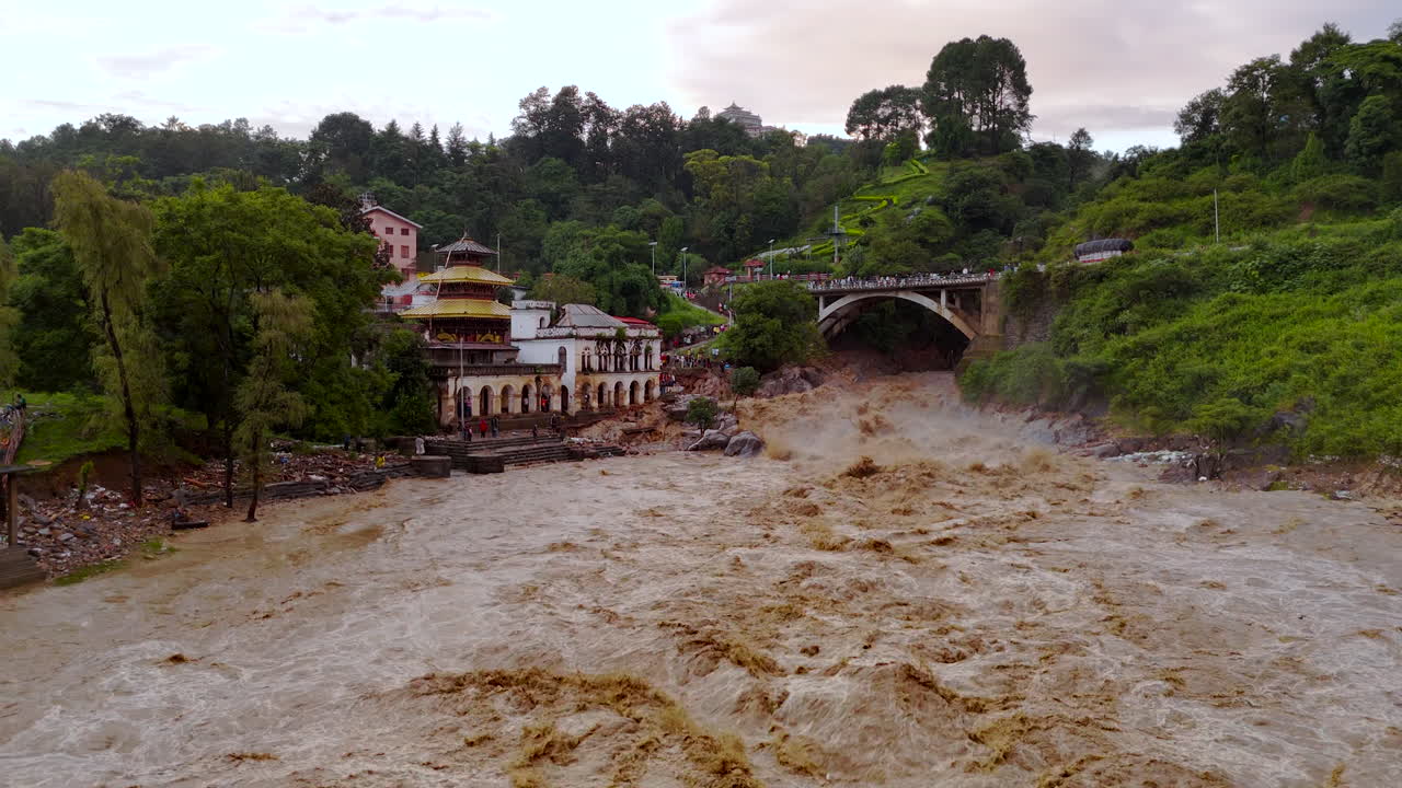 Aerial view of Bagmati river flooding in Kathmandu Nepal near temple landscape reveals destructed riverbanks and residential area cloud bust and climate crisis urgency