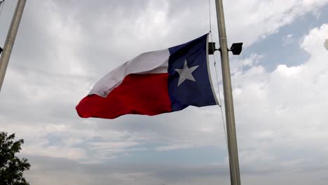 Texas-state-flag-flying-in-the-wind-in-Houston,-Texas-with-a-pan-to-American-flag