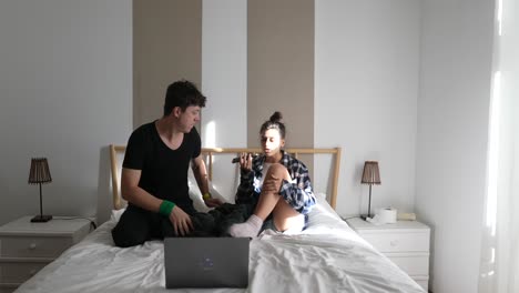 pareja usando portátil y teléfono en el dormitorio
