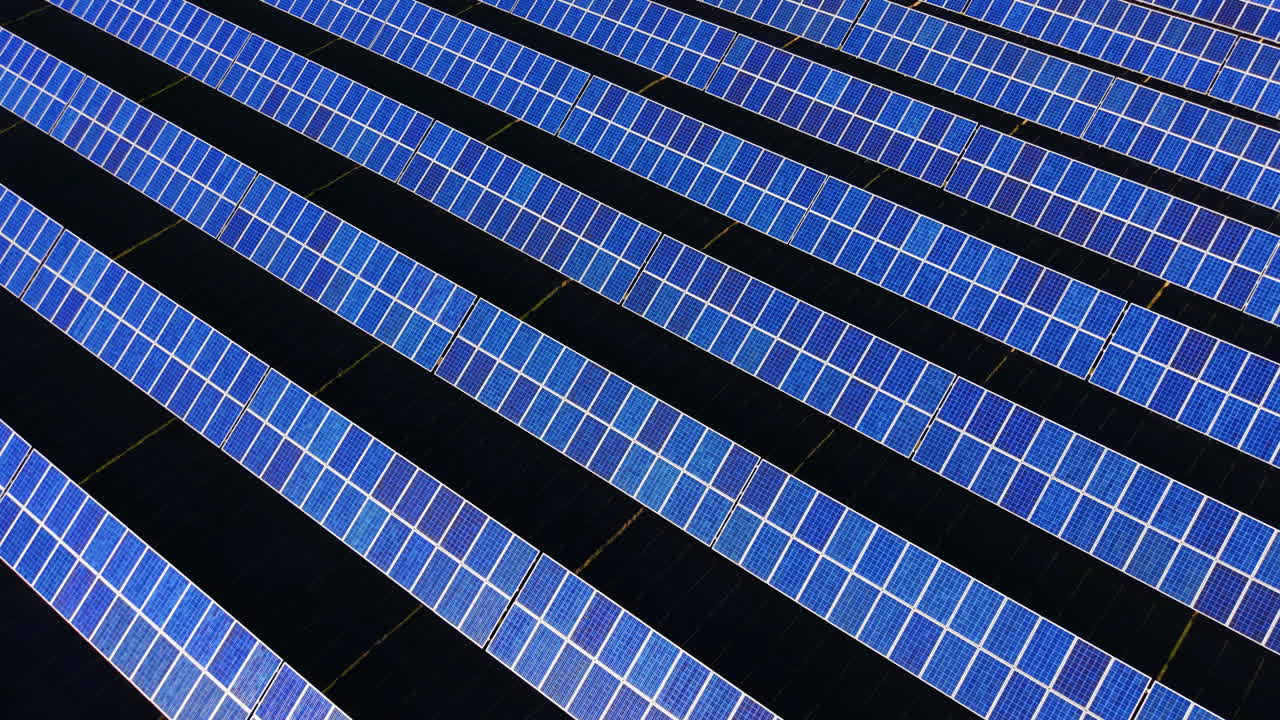 Vista aerea dettagliata di file di moduli solari blu che formano una trama geometrica ripetitiva. Motivo diagonale di pannelli solari fotovoltaici.