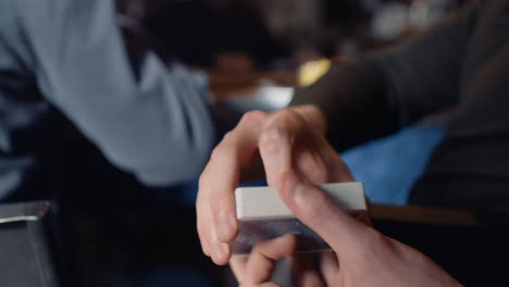 primer plano de un par de manos haciendo un truco de cardistry llamado &quot;primavera&quot;, disparando la baraja de una mano a otra