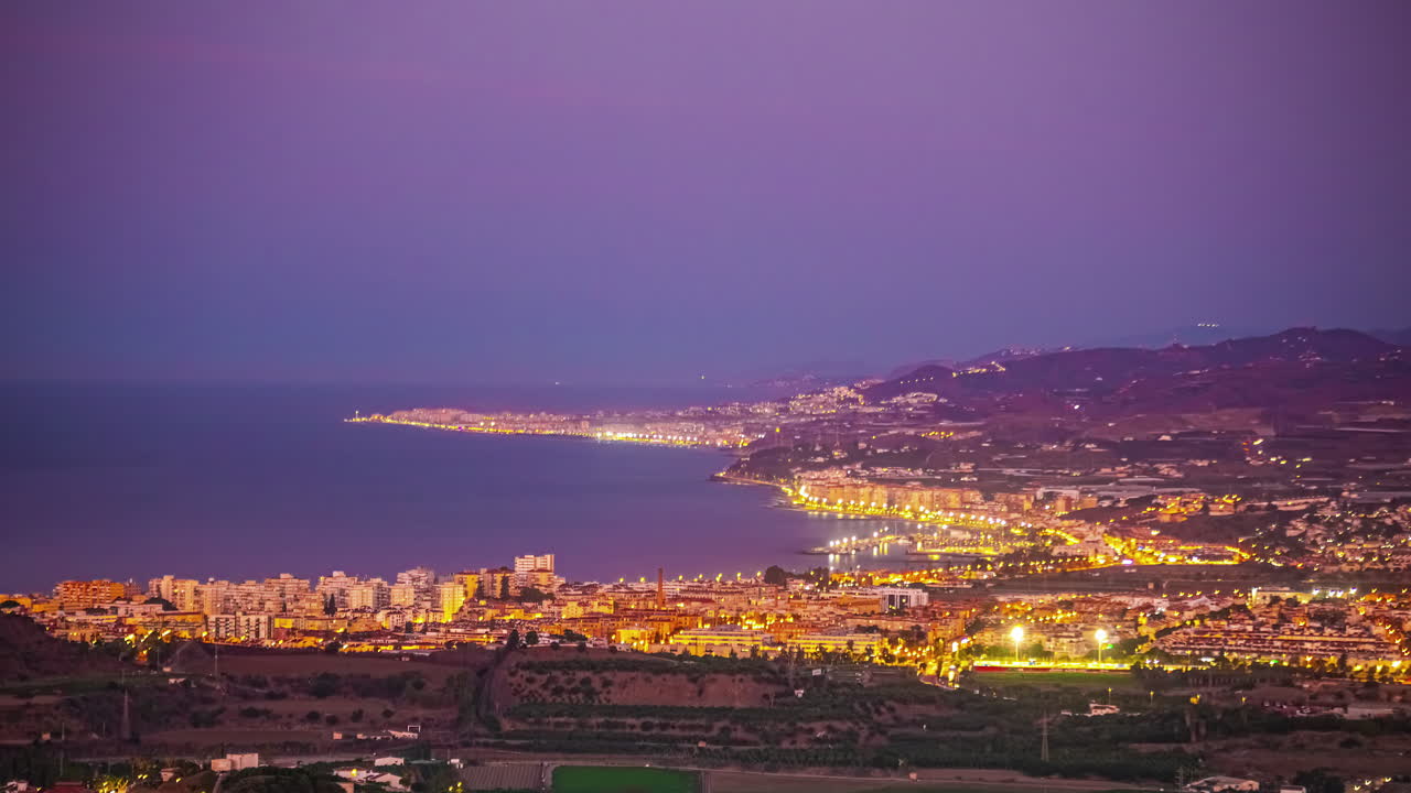 Ampio timelapse dell'alba su una città costiera illuminata di Malaga, Spagna