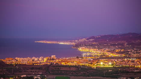 Wide-morning-twilight-timelapse-over-illuminated-coastal-city-of-Malaga,-Spain