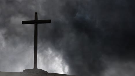 silhouette of a wooden cross against a background of storm and black clouds