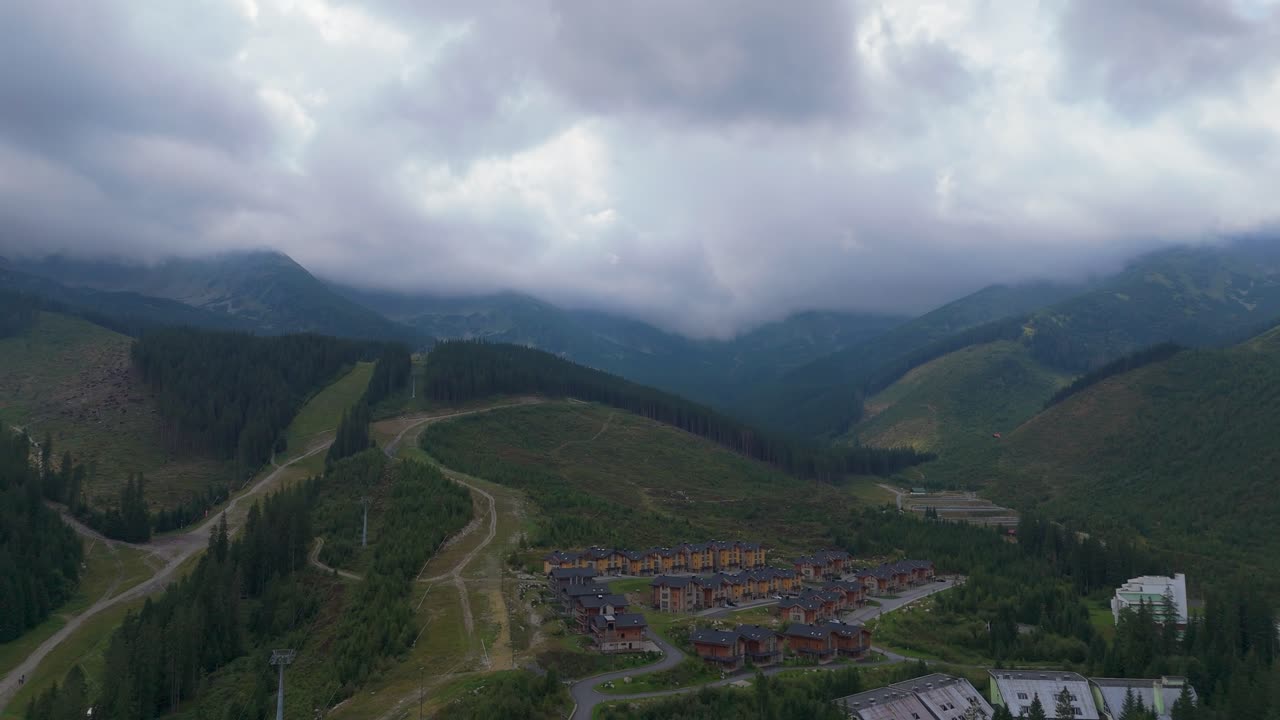 Aerial footage of Demanovska Dolina in Slovakia, showing Jasna ski resort, Vrbicke pleso lake, mountain peaks, and drifting clouds. Beautiful nature and travel visuals from the Zilina region