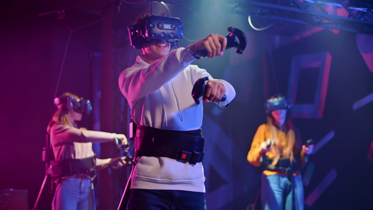 A joyful, interested boy is playing on VR treadmill with helmet, controllers and a backpack. Other people playing nearby