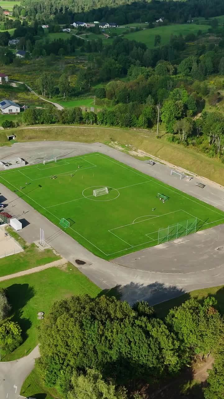 Aerial panorama showing verdant soccer pitch nestled among green landscape, revealing Talsi's scenic environment and sporting infrastructure in Latvia