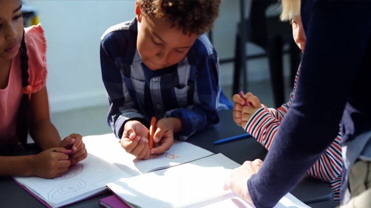 Teacher helping schoolkids with their homework in classroom