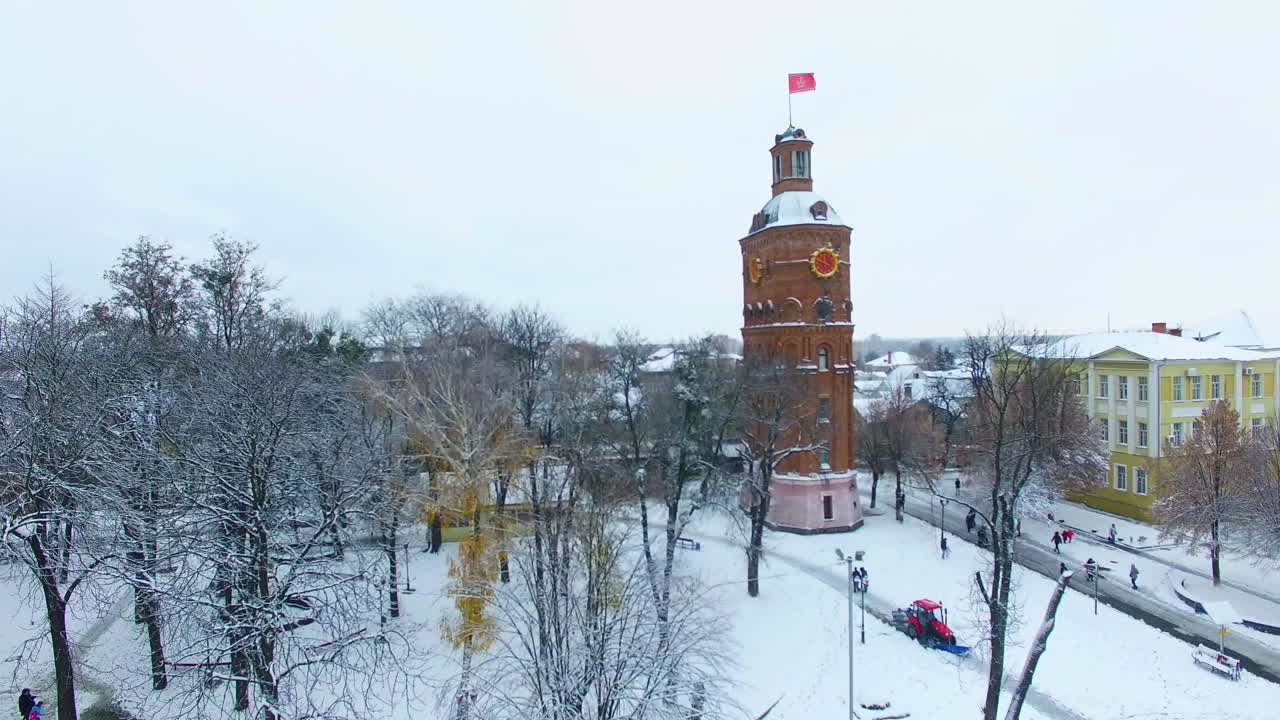 Square with old water tower in the centre of Vinnytsia, Ukraine. Drone ascending over the snowy trees and historic buildings. Aerial view.