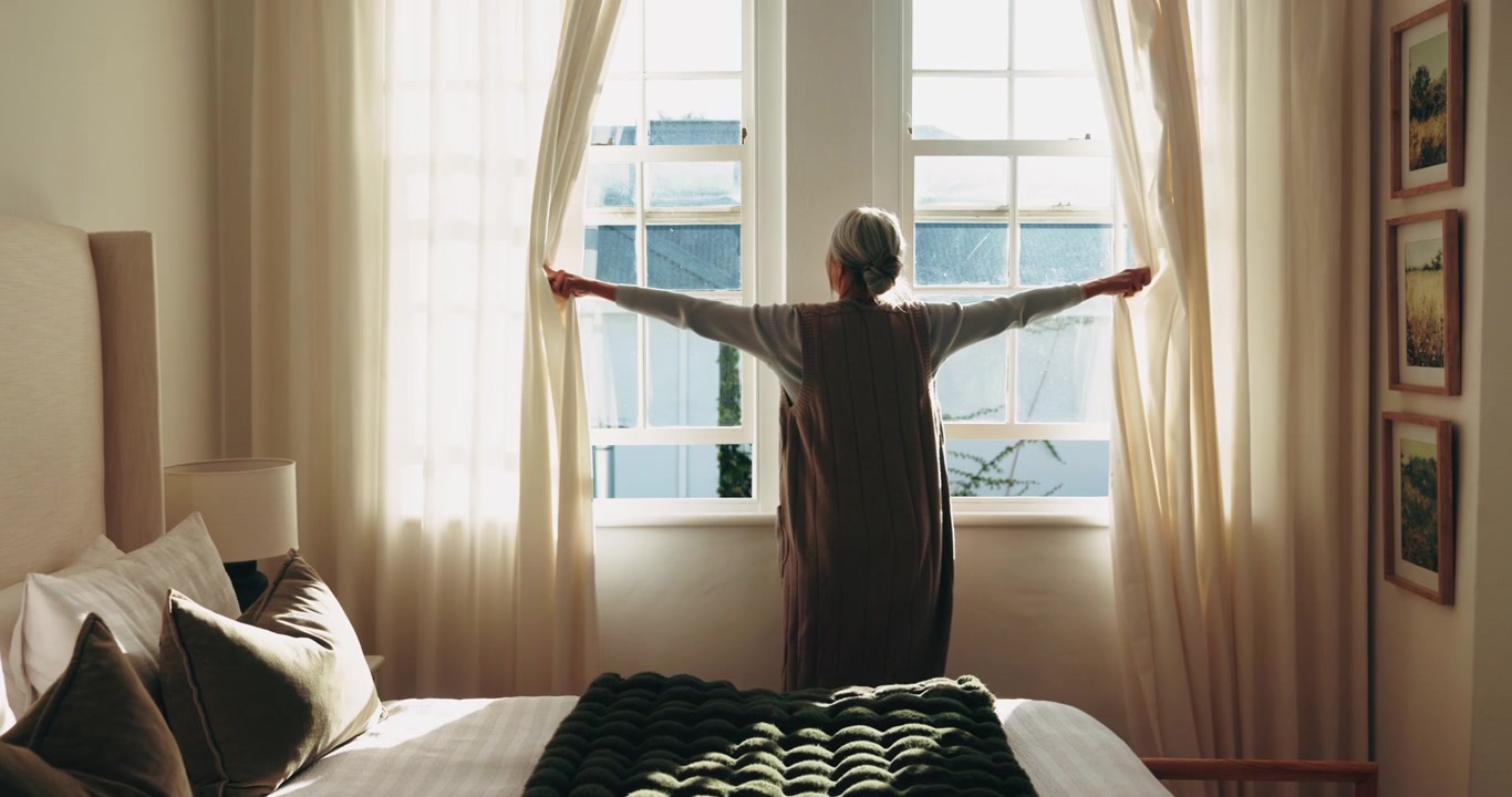 Senior Woman Opening Curtains in Bedroom
