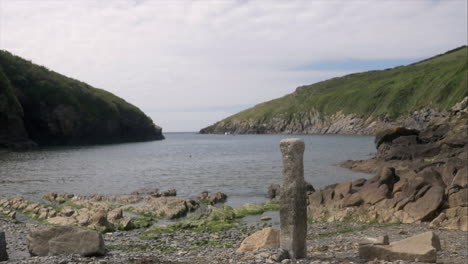 Scenic-view-of-beautiful-coastal-waters-looking-out-from-Port-Quin,-Cornwall,-panning-shot