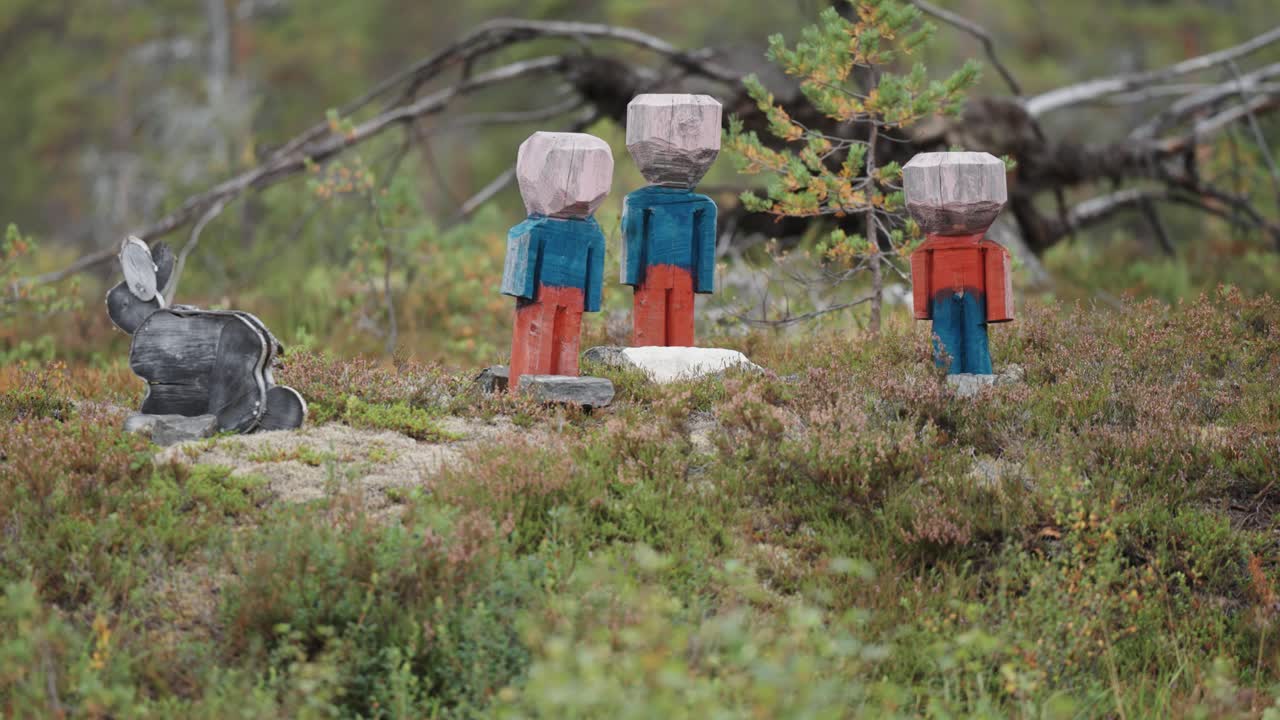 Wooden humanlike statues in the forest opening. Parallax video.
