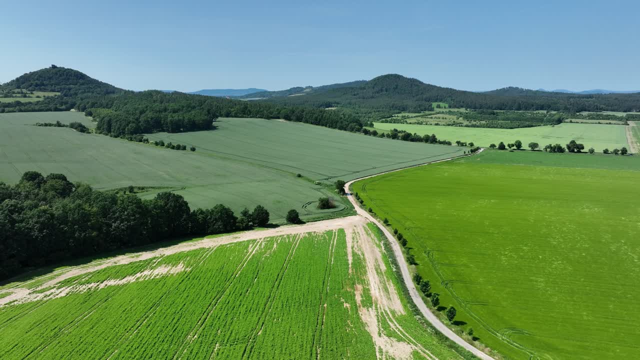 A zoom in reveals large crop fields and forest edges curving toward distant green hills