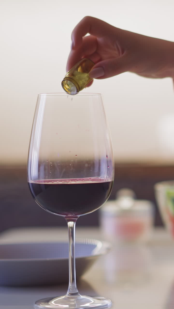 분홍색 드레스를 입은 부인이 잔인한 음료에 독성 가루를 부어 부에서 저녁 식사 중에 복수하기 위해 천천히 움직이는 클로즈업