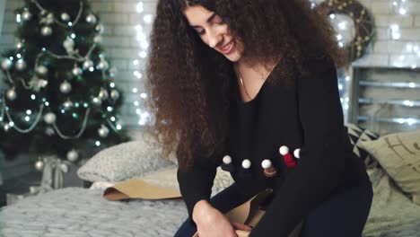 girl packing gift. young beautiful woman wraps christmas gifts while sitting on bed