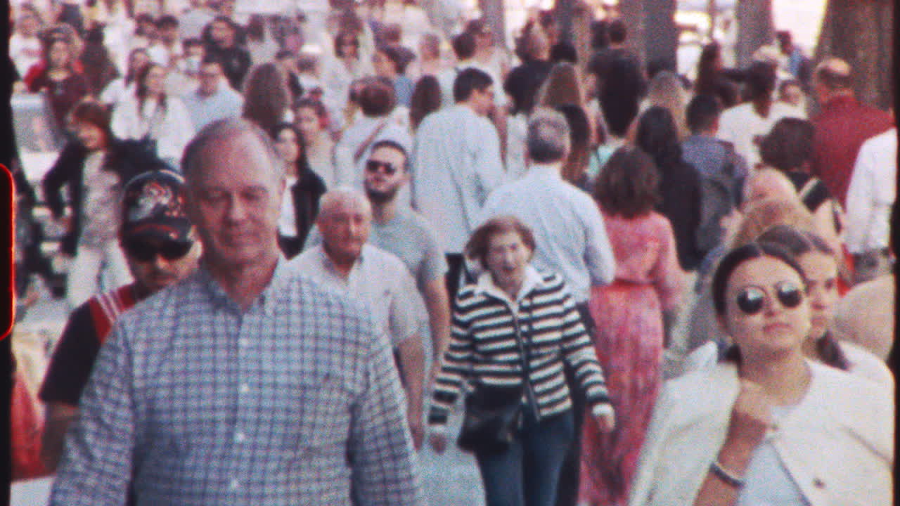 MADRID, SPAIN - JULY 21, 2025: Large group of tourists and locals walking down a busy street in Madrid, Spain, enjoying the sunny weather and urban atmosphere, captured with a vintage film aesthetic