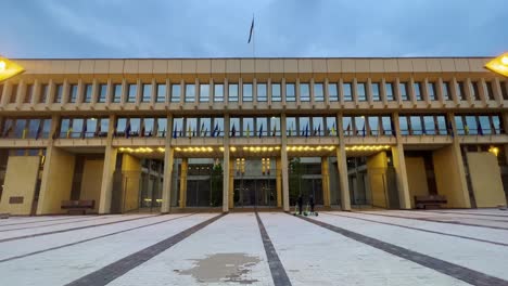 people riding electric scooters in front of vilnius seimas parliament illuminated at sunset in lithuania