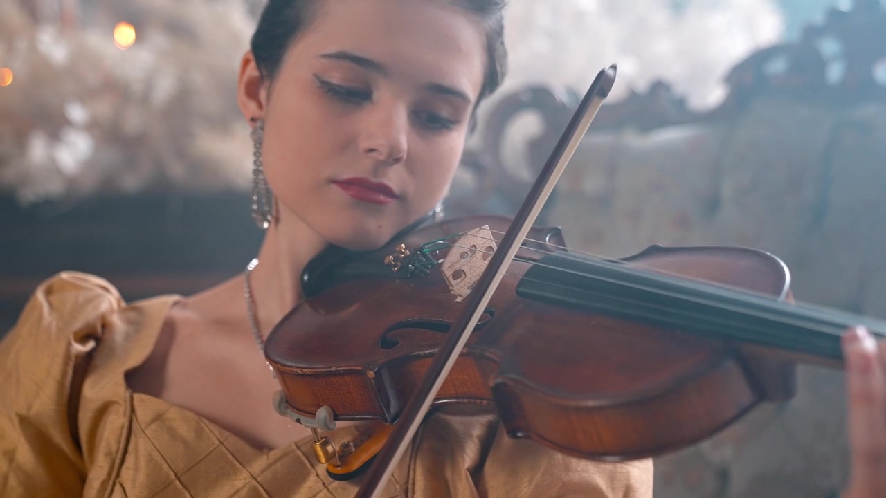 Giovane donna elegante che suona il violino in un ambiente classico