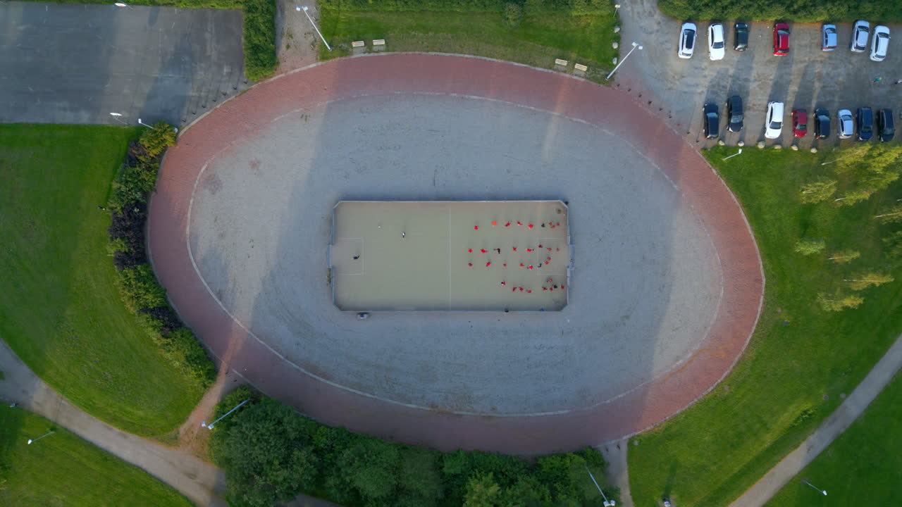 ejercicios de práctica de fútbol en una pequeña jaula de fútbol en un parque, tiro de arriba ancho con la cámara descendiendo