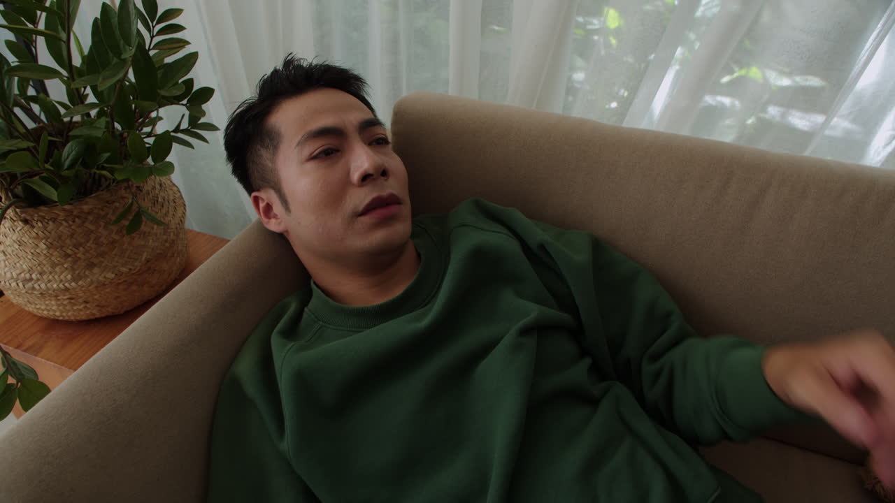 소파에 누워 있는 슬픈 남자