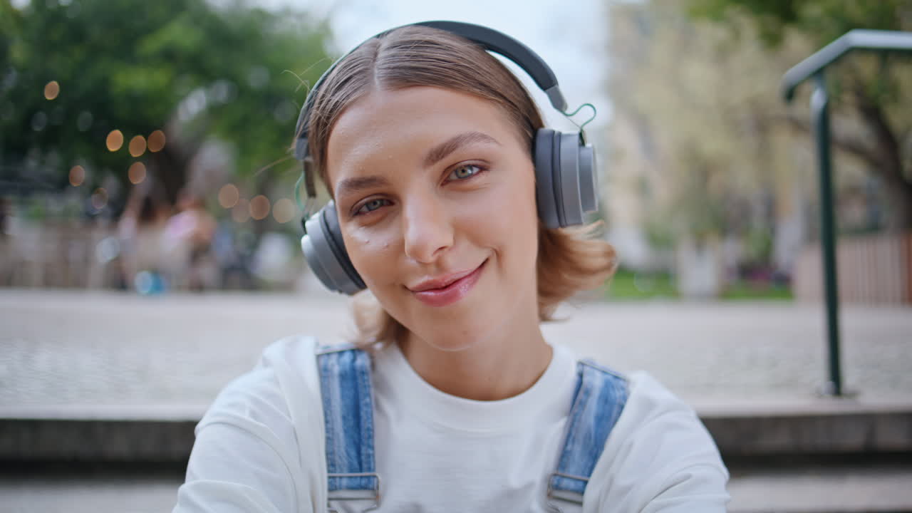 Calm zoomer listening earphones music sitting concrete street stairs closeup